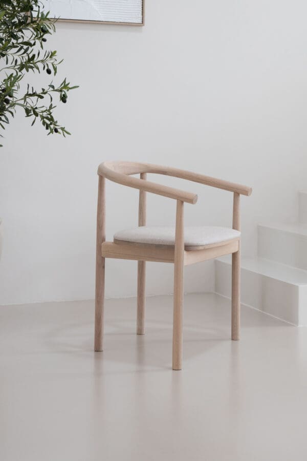 Japandi Esszimmerstuhl Calm mit einem Gestell aus weißem Eichenholz und cremefarbener Sitzfläche in einem minimalistischen Japandi- und skandinavischen Interieur.